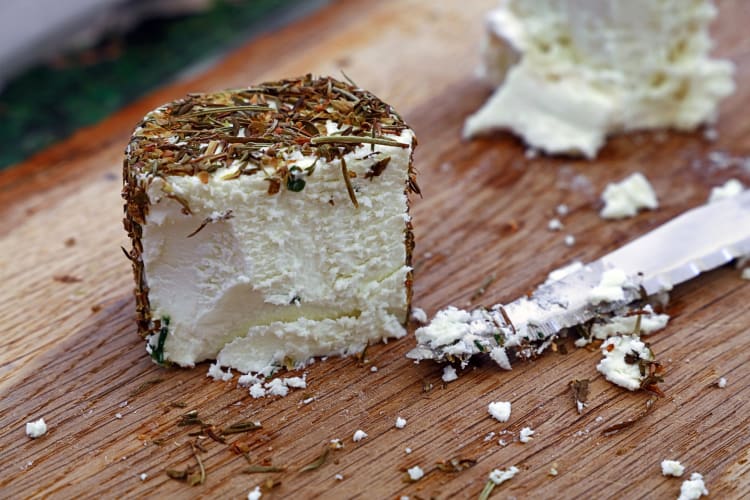 A cut of goat cheese covered in herbs