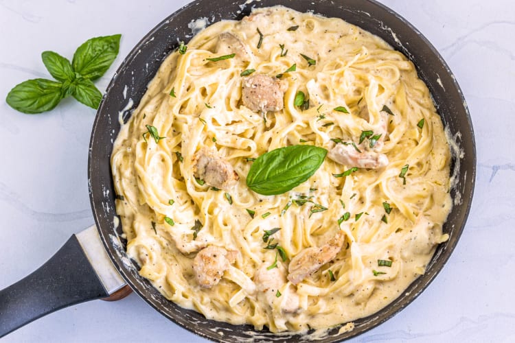 Creamy Tagliatelle pasta in a pan with garnish on top