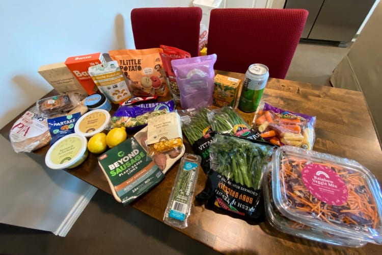 Groceries on a table next to two red dining chairs