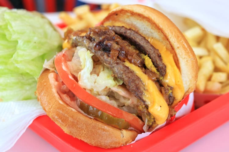 A burger with multiple beef patties on a red tray