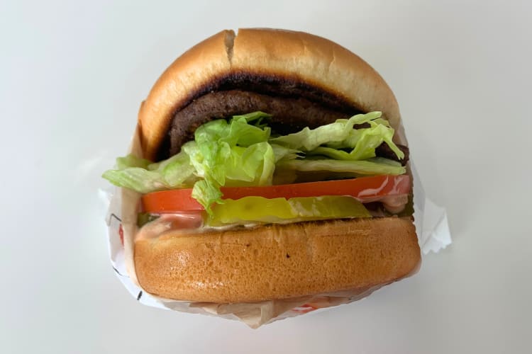 a burger with lettuce, tomatoes and pickles