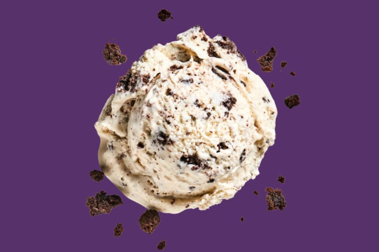 A scoop of cookies and cream ice cream on a purple background