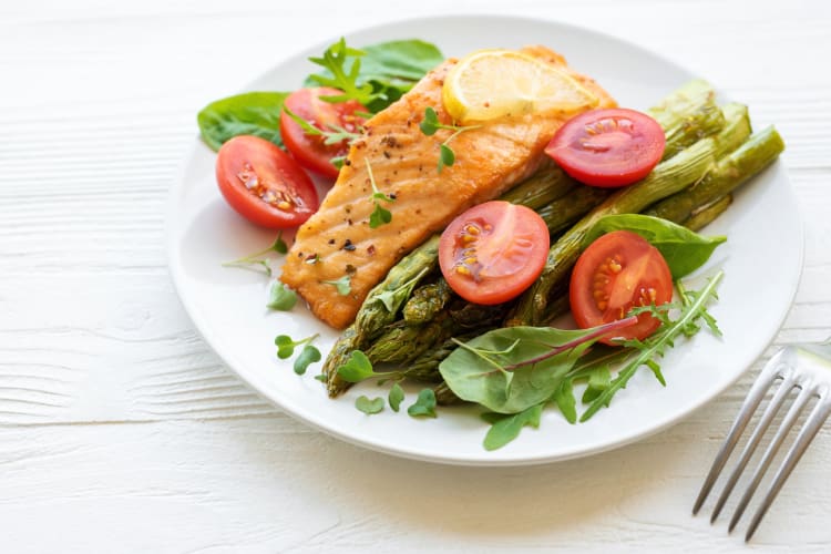 Salmon on a plate with asparagus, cherry tomatoes and salad greens