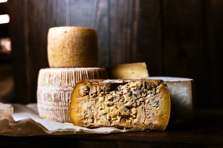 Different wheels of cheese, one being sliced in half