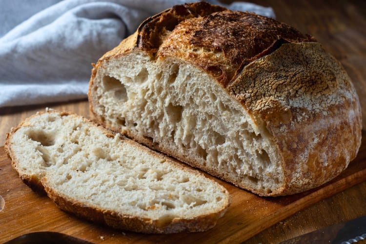 Bread on brown wooden chopping board.