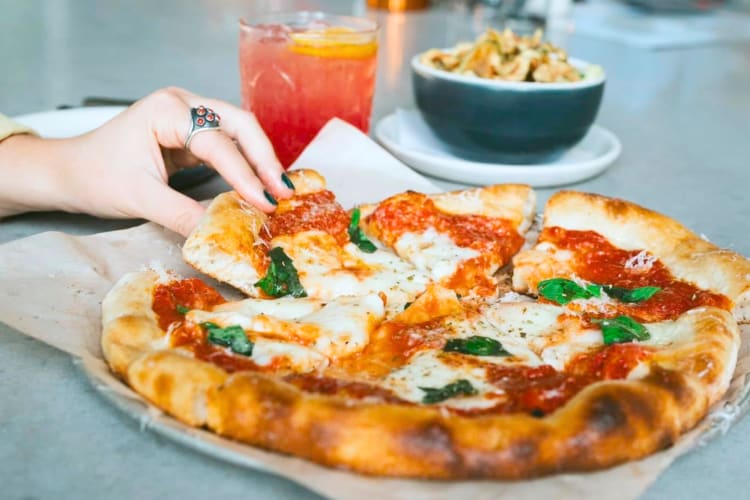 A person taking a slice from a pizza