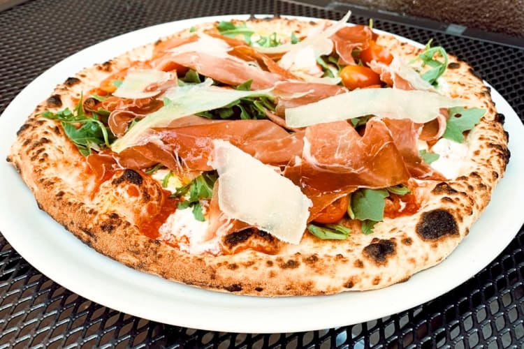 A pizza with prosciutto and grated Parmesan