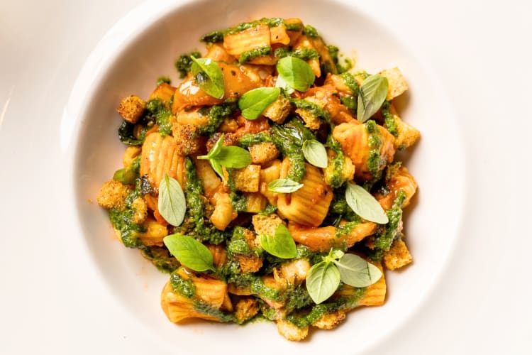 A bowl of tomato rigatoni with basil and pesto