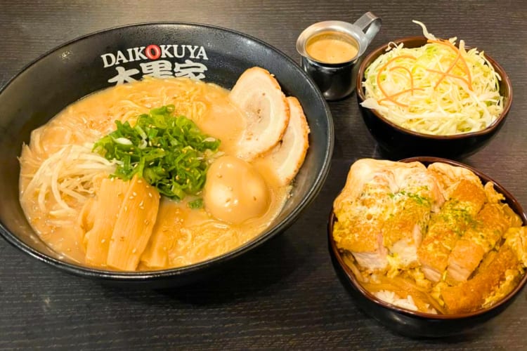 Ramen and a chicken dish on a black table