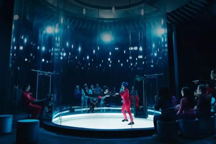 person indoor skydiving with a small audience