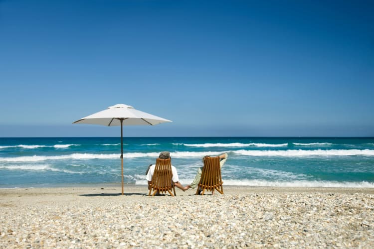 couple on deck chairs holding hands on the beach