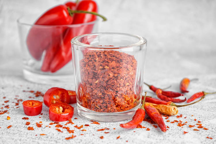 Glass of Chipotle Chili Flakes on Light Background