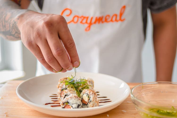 person garnishing finished sushi dish