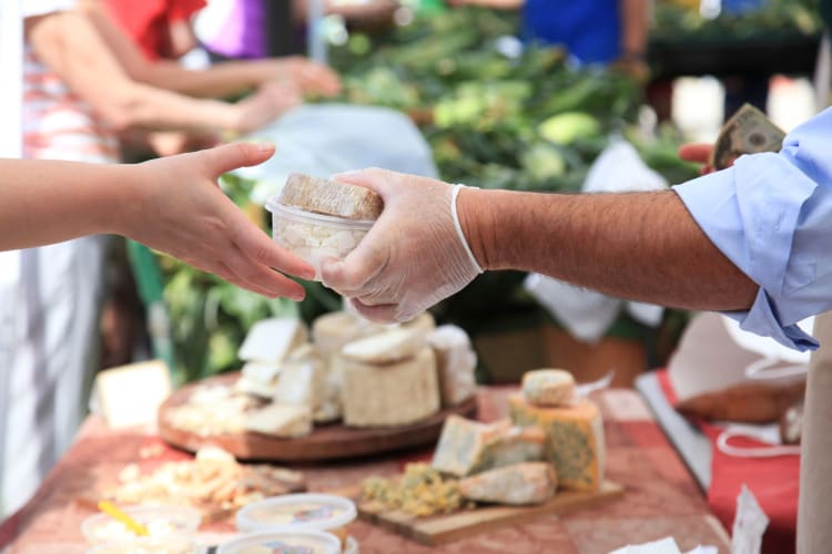 goods exchange hands at a cheese stall at a farmers market