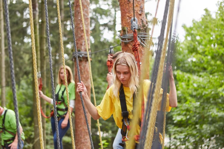 Young Woman Anxiously Balances in the High Ropes Course