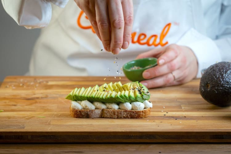 Cozymeal chef seasoning avocado slices on bread