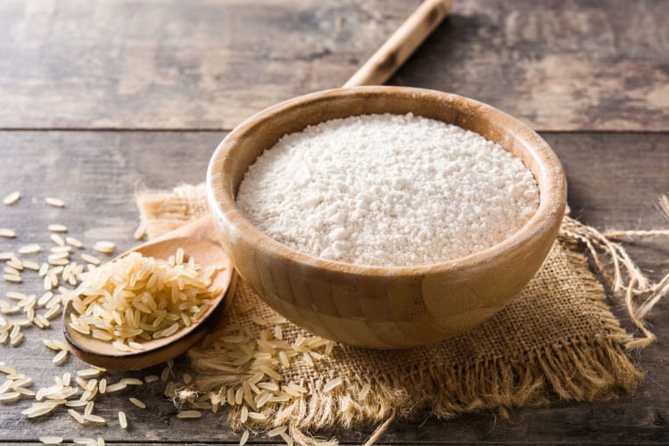 brown rice flour in a bowl next to some rice