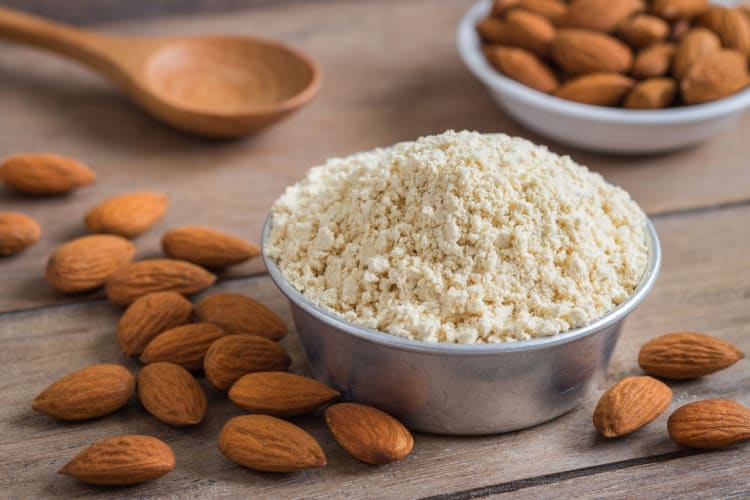 almond flour in a bowl surrounded by scattered almonds