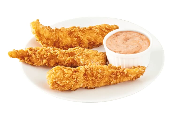 Three Jollibee chicken tenders on a plate next to a bowl of sauce