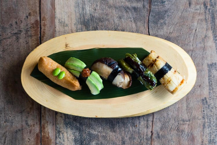 Aerial shot of five different pieces of sushi on a wooden board, from Kata Robata