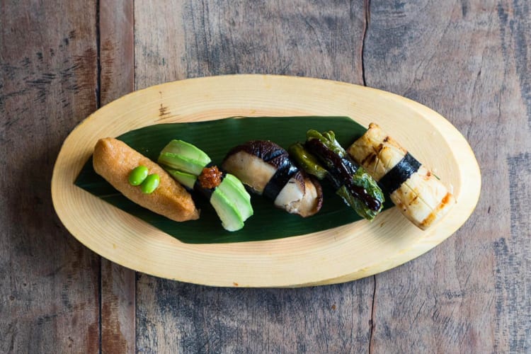 Aerial view of five different pieces of sushi on a wooden board, from Kata Robata