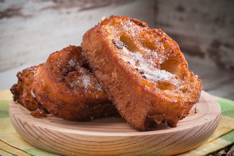 Two large slices of French toast on a wooden serving board