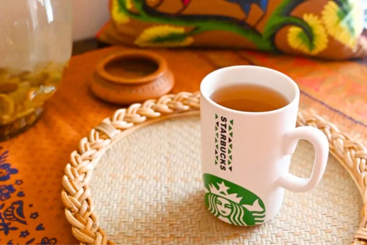 A Starbucks mug with tea in it on a mat