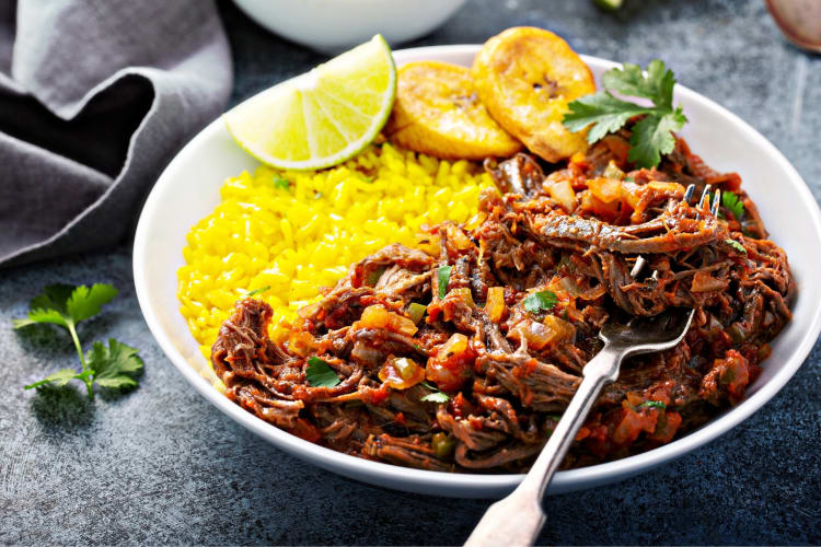A shredded beef dish with plantains, rice and lime