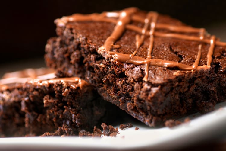 Close-up of two brownies with fudge icing on top