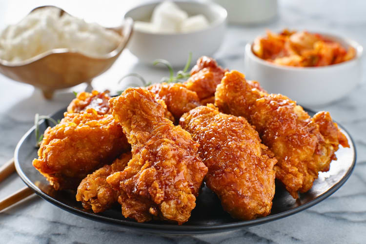 Korean fried chicken wings in the foreground with other dishes in the background