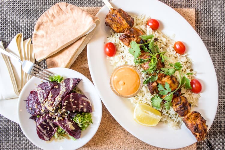 A chicken kebab with rice, pita and beet salad