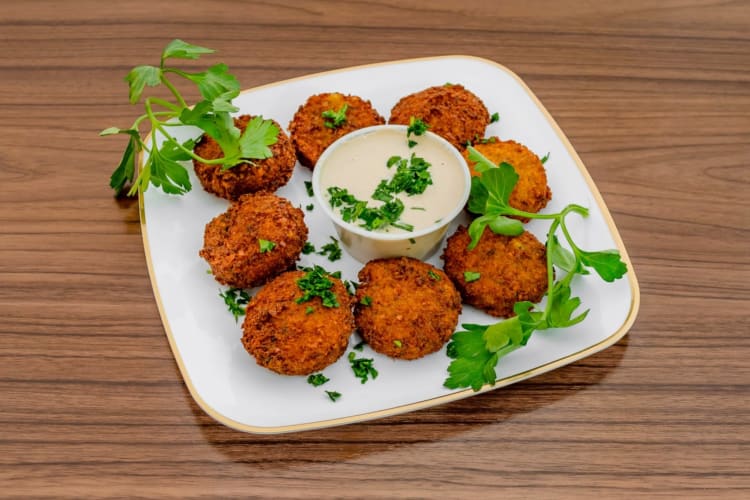 A plate with falafel, cilantro and a dip