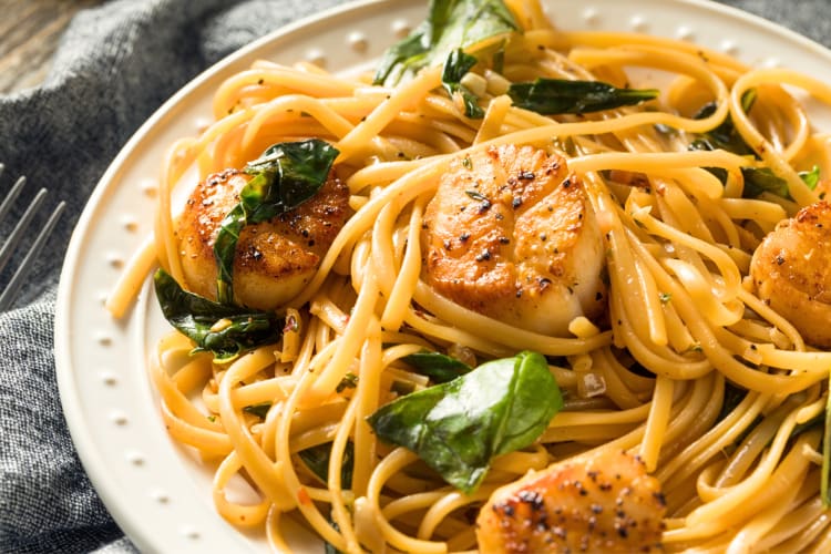 Scallop linguini pasta dish with green leaves on top