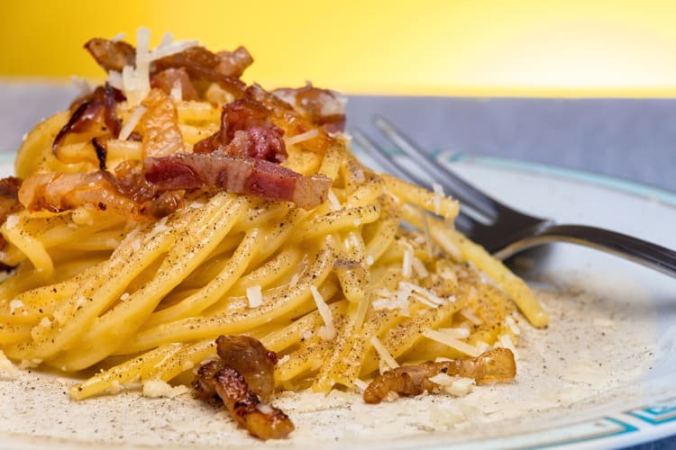 Close-up of spaghetti carbonara on a plate with a fork next to it