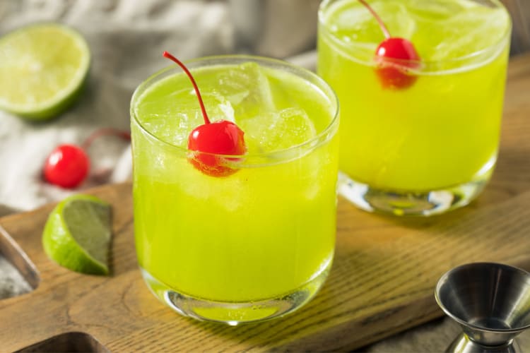 Two green drinks with cherries on top