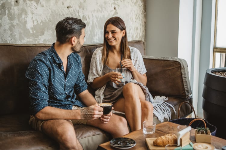 Two people on a couch having coffee