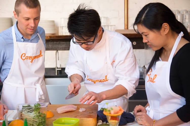 Two people taking a cooking class with a chef, booked through Cozymeal