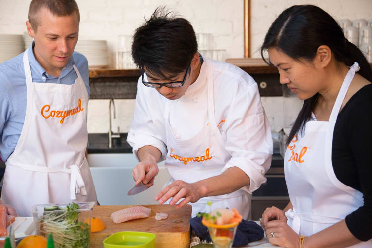 Two people taking a cooking class with a chef, booked through Cozymeal