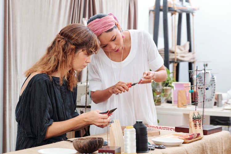 One woman teaching another how to make jewelry