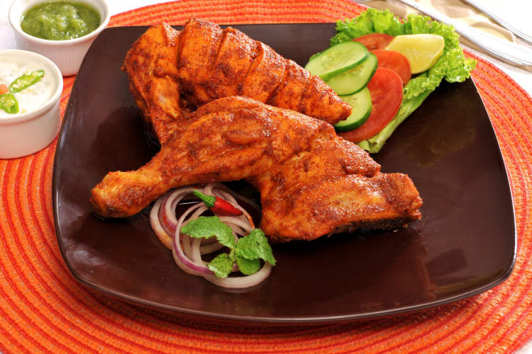 Two pieces of airline chicken on a plate with a side salad