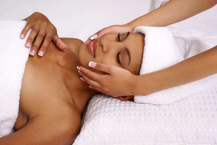 A lady relaxes at the spa while receiving a facial treatment.