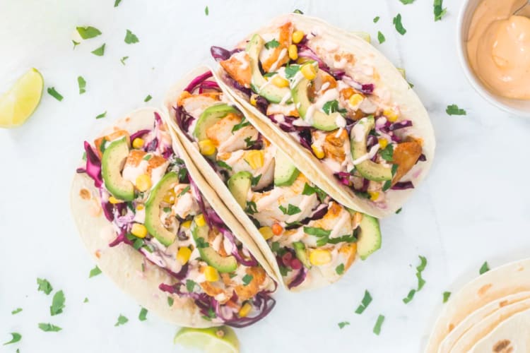 Three fish tacos with cabbage and avocado