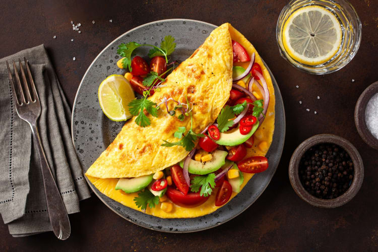 An omelette next to lemon water and seasonings