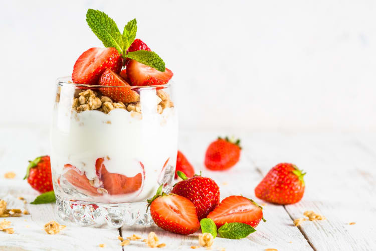 A strawberry parfait next to fresh strawberries