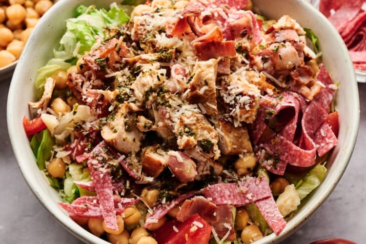 A bowl of salad with bacon and chicken