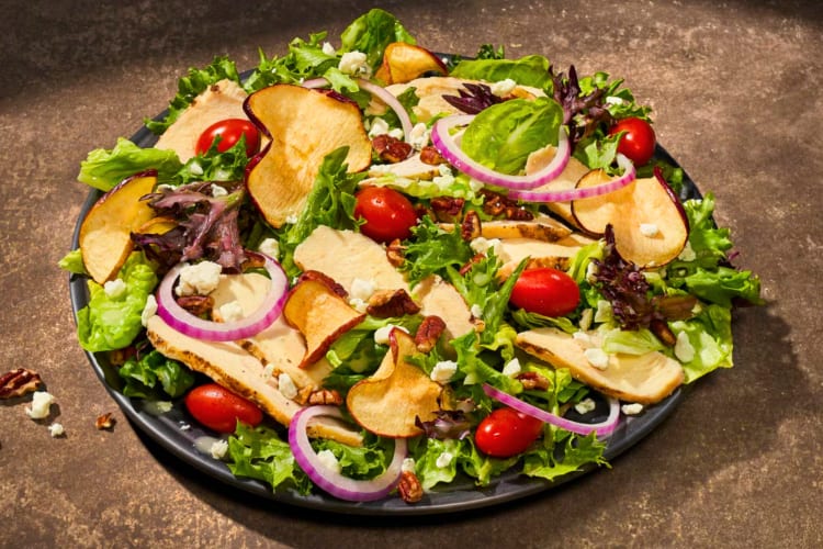 A Panera Fuji Apple Salad with dried apple, red onion, tomatoes and lettuce