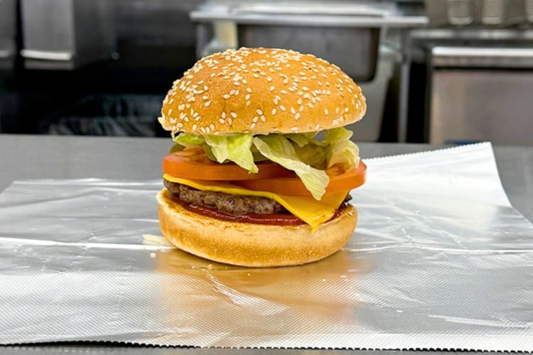 A burger with lettuce, tomato and cheese on a counter