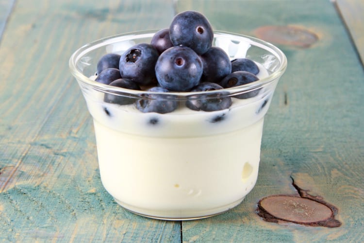 A cup of yogurt with blueberries on top