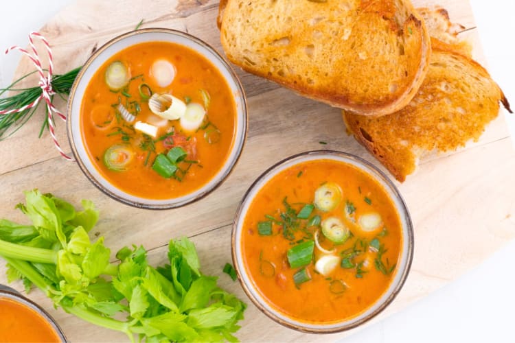 Bowls of tomato soup next to grilled cheese