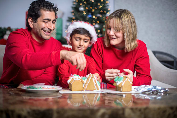 A father, mother and son making a gingerbread house as a family Christmas tradition